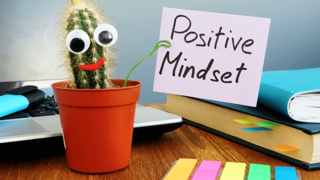 A cactus in a flower pot with a sign that reads positive mindset
